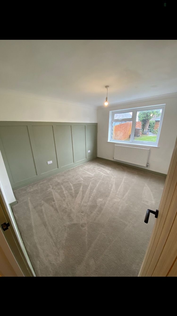 A bedroom with green shaker panelling