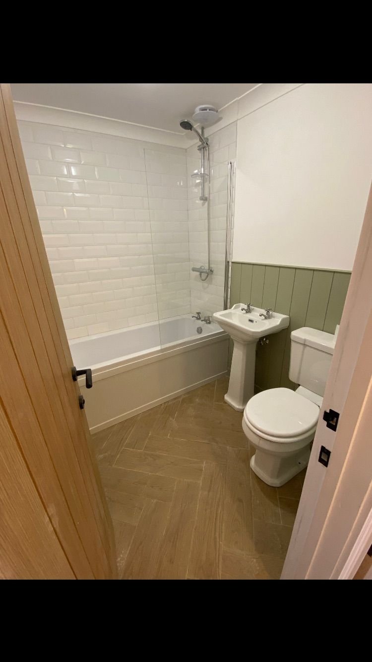 A bathroom with sage panelling and white metro tiles