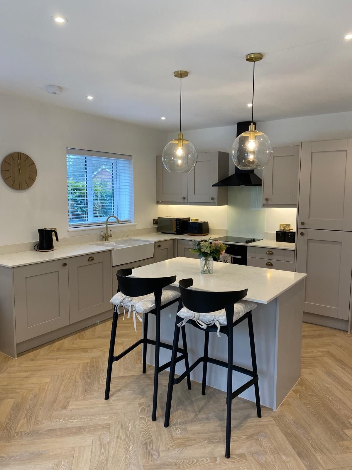 A shaker kitchen with a quartz island and Belfast sink