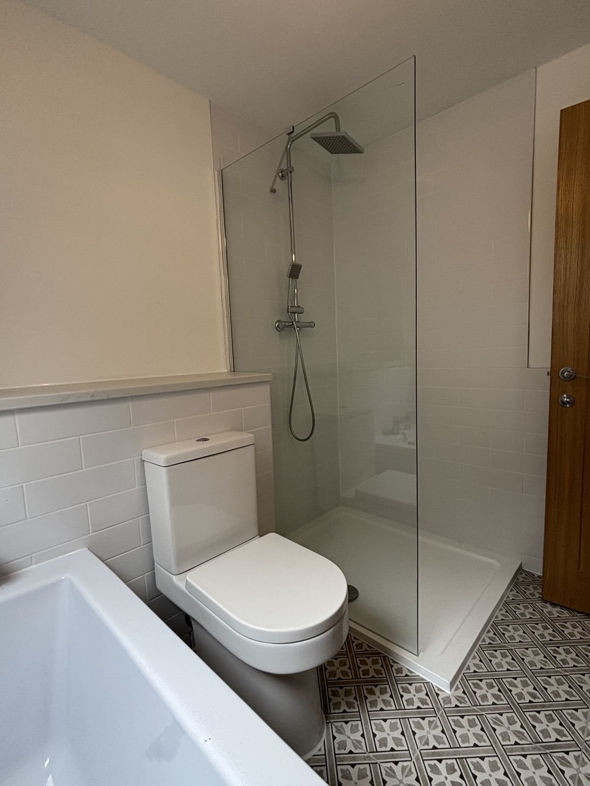 A walk-in shower with patterned floor tiles