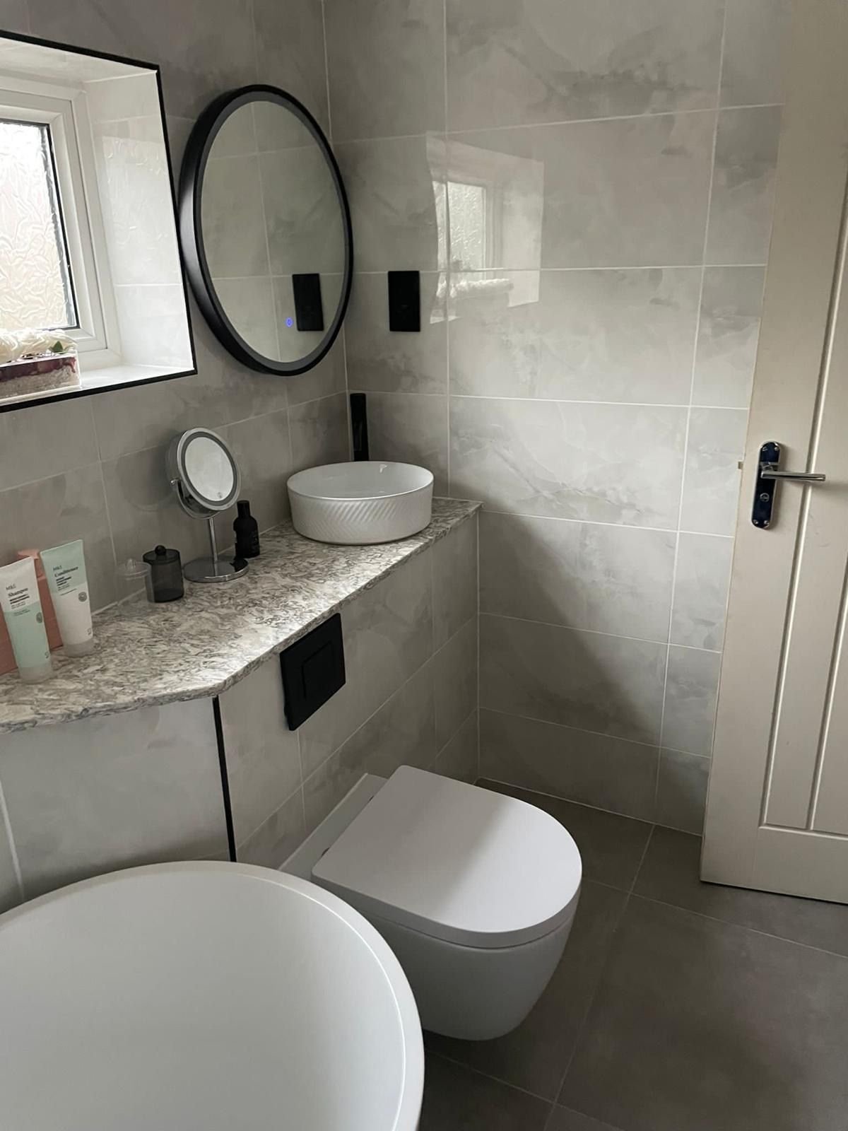 A wall-hung toilet and a basin on a stone shelf
